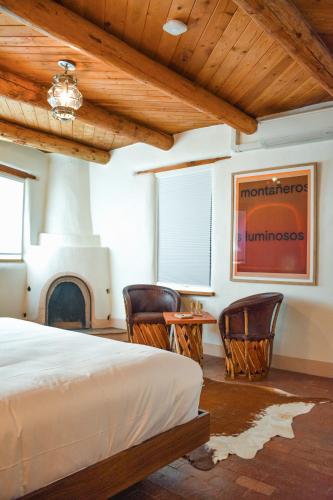 a bedroom with a bed and chairs and a fireplace at The Parador in Santa Fe