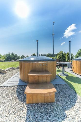 a circular building with a bench in a park at Nowa Dana Ośrodek Wypoczynkowy in Łebcz
