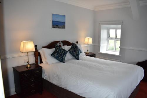 a bedroom with a bed with white sheets and pillows at Aran View Holiday Home in Doolin