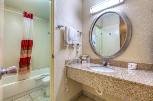 a bathroom with a shower, sink, and mirror at Red Roof Inn Tulsa in Tulsa