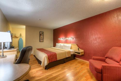 a room with a bed, chair, desk and a lamp at Red Roof Inn Tulsa in Tulsa