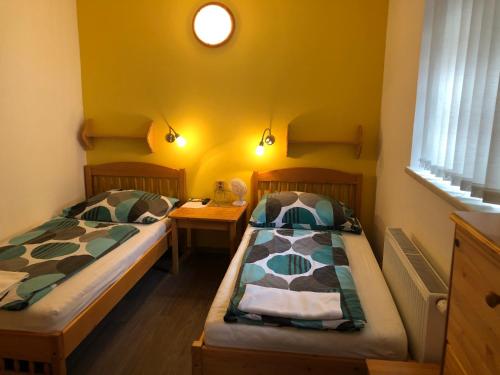 two beds in a room with yellow walls at Pension Kadlcuv Mlyn in Brno