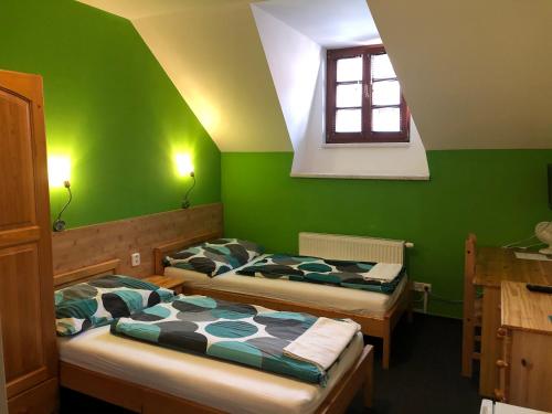 ブルノにあるPension Kadlcuv Mlynの緑の壁と窓が特徴の客室で、ベッド2台が備わります。