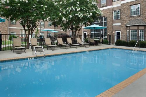 une grande piscine bleue avec des chaises et des parasols dans l'établissement Staybridge Suites Greenville I-85 Woodruff Road, an IHG Hotel, à Greenville