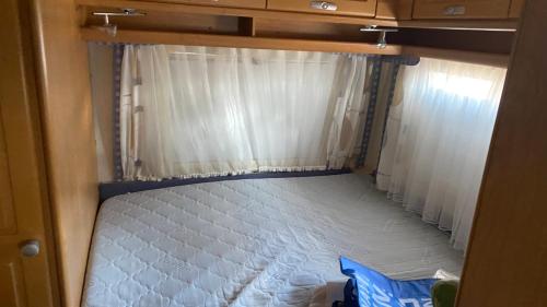 a small bedroom with a bed in an rv at Adria Caravan (with air conditioner) in Privlaka