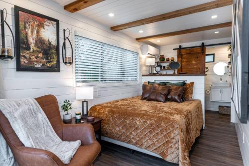 a bedroom with a bed and a chair at Deer Creek Tiny Container Home-12 Min to Magnolia in Bellmead
