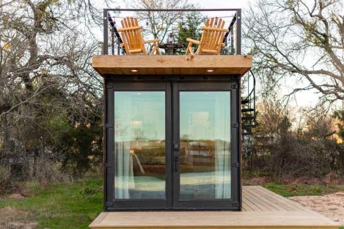 a tiny house with two chairs on top of it at Deer Creek Tiny Container Home-12 Min to Magnolia in Bellmead