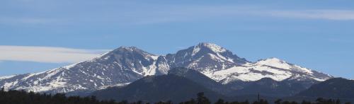 a snow covered mountain range with trees in the foreground at Olympus Lodge in Estes Park