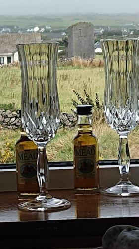 two wine glasses sitting next to a bottle of alcohol at Doolin Lanelodge -Room Only- in Doolin