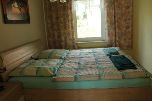 a bed with a quilt and a window in a bedroom at Ferienhaus Groß Dratow in Groß Dratow