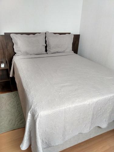 uma cama com lençóis brancos e almofadas num quarto em Plaza Fraga Maia em Feira de Santana
