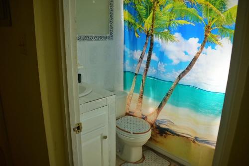La salle de bains est pourvue d'une fresque murale représentant une plage et de toilettes. dans l'établissement Unity Villa 3 bedroom with fans Wifi Parking, à Montego Bay
