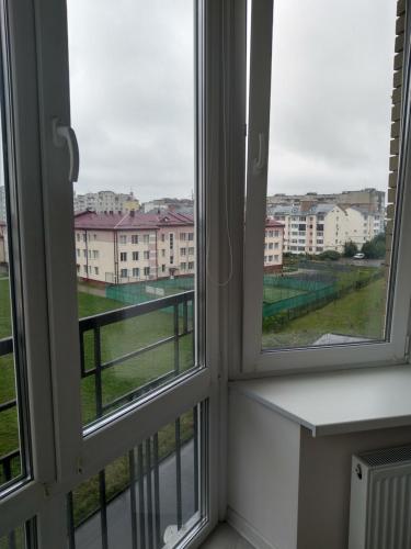 Zimmer mit 2 Fenstern und Blick auf ein Gebäude in der Unterkunft Apartment Ivashchenka 1a in Luzk
