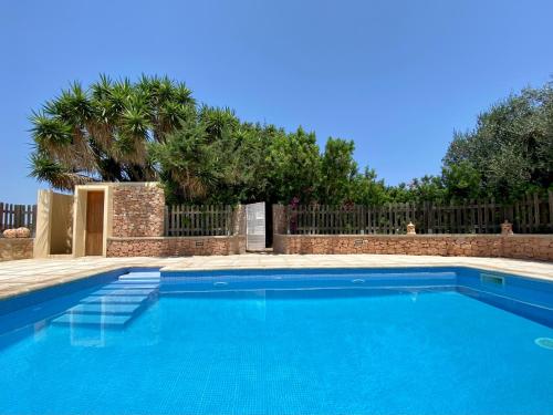 a blue swimming pool with a fence and trees at Can Xicu Castello in Sant Ferran de Ses Roques