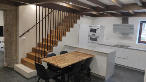 uma cozinha com uma mesa de madeira e uma escada em A Casa de Costa em Laxe