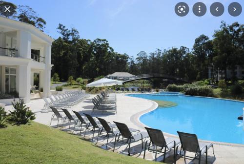 a row of chairs next to a swimming pool at Green Park 2 Ambientes con Balcón Vista Bosque o Laguna con Parrillero in Punta del Este