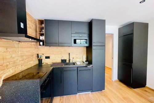 - une cuisine avec des armoires noires et un réfrigérateur noir dans l'établissement Serre-ChevalierStudio Terrace next to ski slopes, à Saint-Chaffrey
