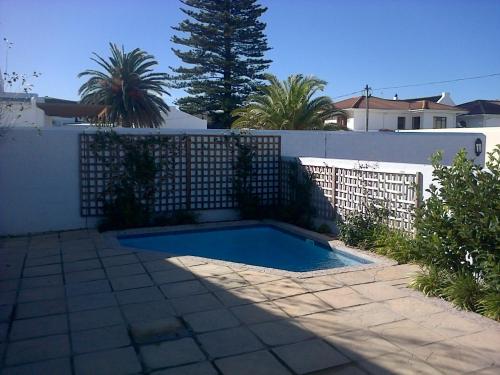 a swimming pool in front of a white fence at Kenjockity Self Catering Apartments in Hermanus