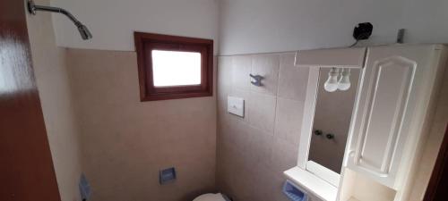 a bathroom with a toilet and a window at Hotel Capri in Villa Gesell