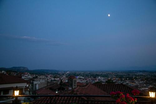 a view of a city at night with the moon at Under the rocks meteora panoramic view villa in Kalabaka