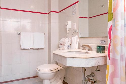 a white bathroom with a toilet and a sink at Ayenda Frida Costa Azul in Mexico City