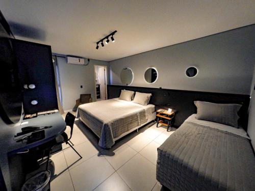 a bedroom with a bed and a desk with a television at Castro's Hotel in Telêmaco Borba