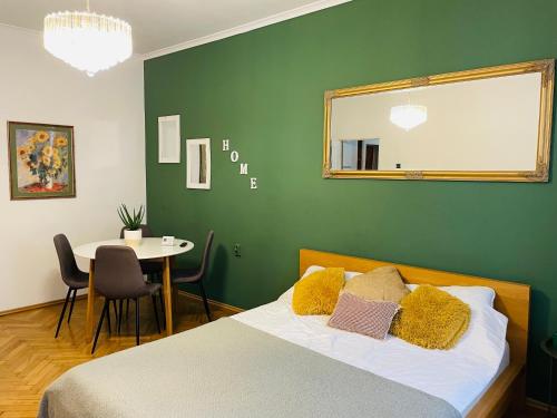 a green bedroom with a bed and a table at Postavarului Apartment in Braşov