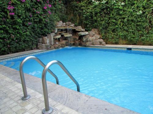 a large blue swimming pool with a rock waterfall at Best Western Hotel Posada Del Rio Express in Torreón