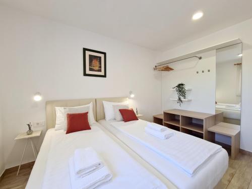 two beds in a small room with a mirror at OrkulaBliss Apartments in Pašman
