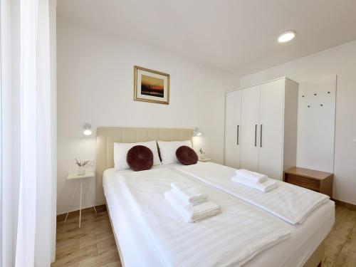 a bedroom with a large white bed with towels on it at OrkulaBliss Apartments in Pašman