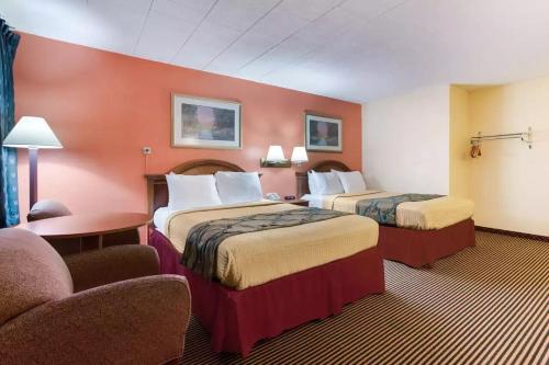 a hotel room with two beds and a chair at Royal Inn Clearfield in Clearfield