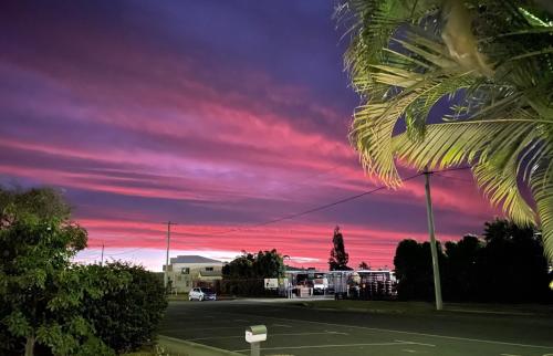 een zonsondergang boven een parkeerplaats met een palmboom bij AAOK Riverdale Caravan Park in Bundaberg