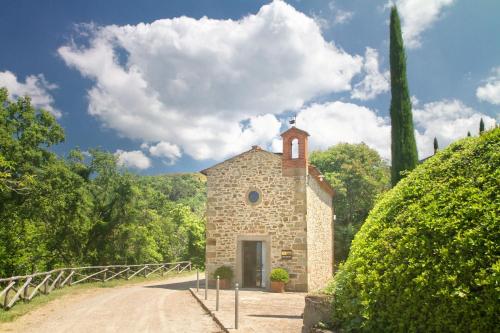 a small stone building with a clock tower on a road at Odina Agriturismo in Loro Ciuffenna