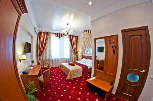 a hotel room with a bed and a desk at Milyutinsky Hotel in Cherepovets