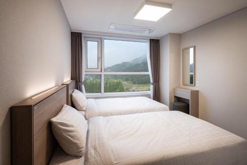 a bedroom with two beds and a large window at Kumho Hwasun Spa Resort in Hwasun