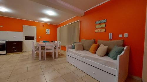 sala de estar con sofá y pared de color naranja en La Pausa en Tandil