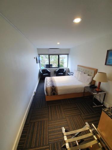a bedroom with a bed and a room with a couch at Paihia Pacific Resort Hotel in Paihia