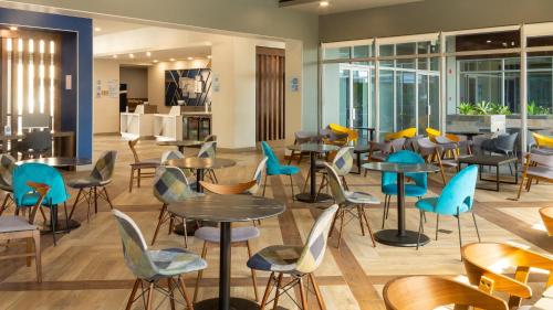 un restaurant avec des tables, des chaises et des fenêtres dans l'établissement Holiday Inn Express & Suites - Tijuana Otay, an IHG Hotel, à Tijuana
