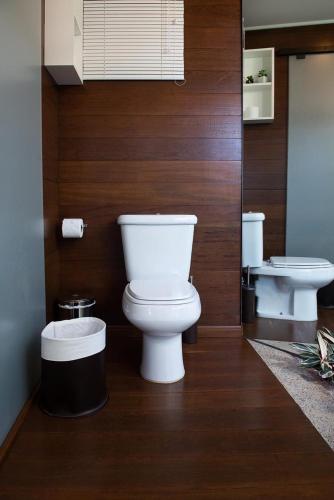 a bathroom with a white toilet and a wooden wall at Morada Prainha in Garopaba
