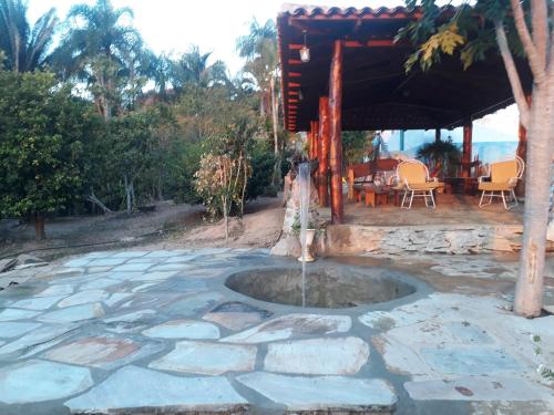 une terrasse en pierre avec une fontaine en face d'une maison dans l'établissement Sítio Lavras do Abade, à Pirenópolis
