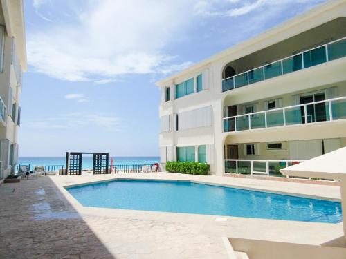 a large building with a swimming pool next to the ocean at Departamento sobre la playa Cancun in Cancún