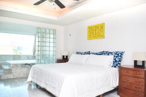 a bedroom with a white bed and a window at Departamento sobre la playa Cancun in Cancún