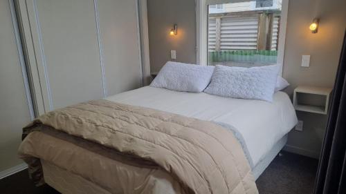 Un dormitorio con una cama blanca con almohadas y una ventana. en 9 Leamington Street, en Hanmer Springs