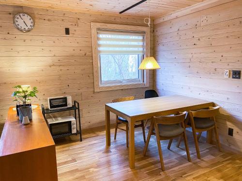a dining room with a table and chairs and a clock at BAAN HAKUBA in Hakuba