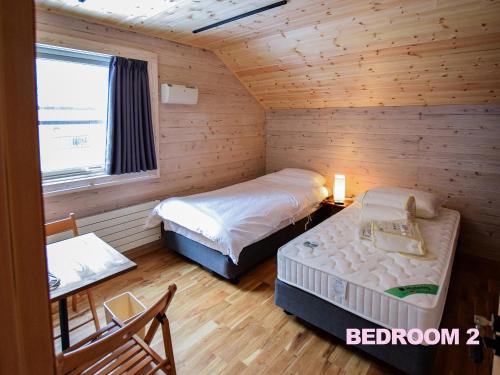 a bedroom with two beds in a log cabin at BAAN HAKUBA in Hakuba