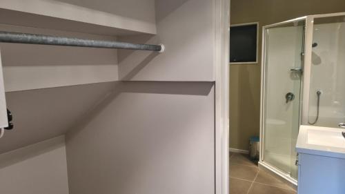 a white bathroom with a shower and a sink at 23a Leamington Street in Hanmer Springs