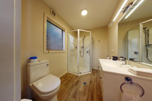 a bathroom with a toilet and a shower and a sink at Heritage Court Motor Lodge Oamaru in Oamaru