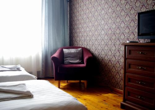 a bedroom with a chair and a dresser with a television at Villand Hotel with Free Private Parking and Self Check In in Rīga