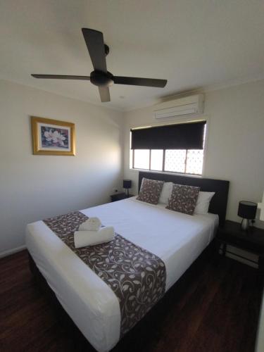 a bedroom with a large bed with a ceiling fan at Cascade Motel In Townsville in Townsville