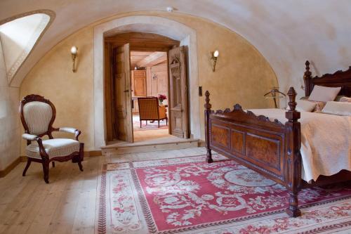 a bedroom with a bed and a chair and a doorway at Schloss Matzen in Reith im Alpbachtal